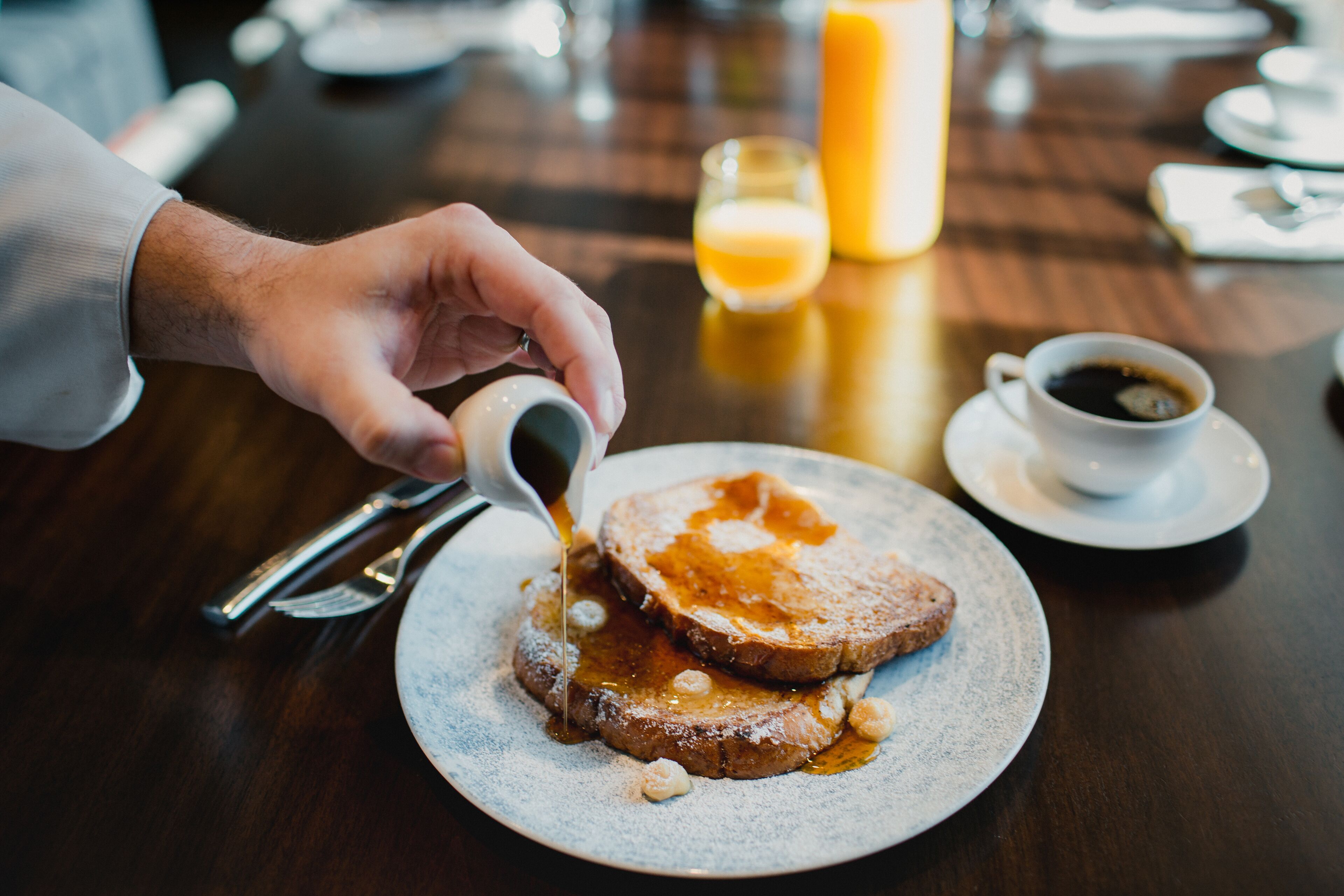 A breakfast setting with toast, syrup, and a cup of coffee on a table.