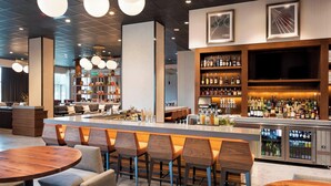 Zona de bar moderna con una barra larga, taburetes y una variedad de botellas.