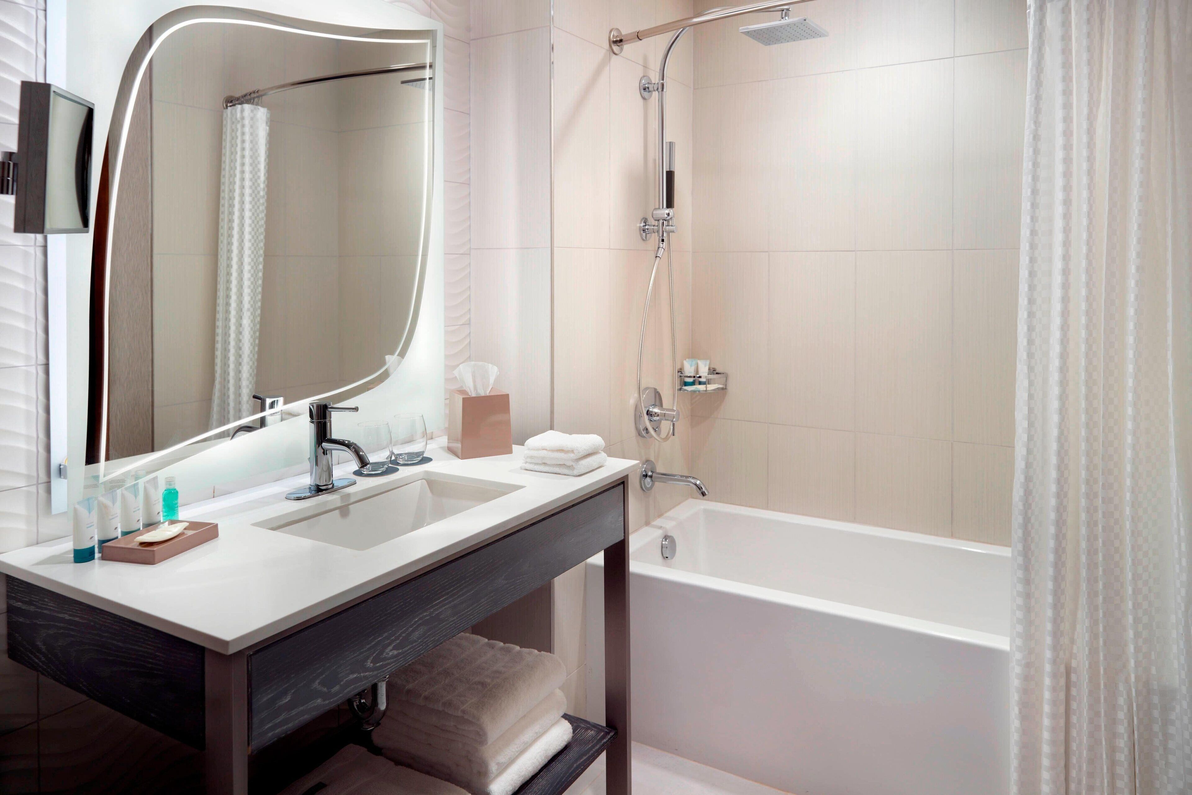 Een moderne badkamer met een wastafelmeubel met dubbele wastafel, een grote spiegel, een bad en een douche.