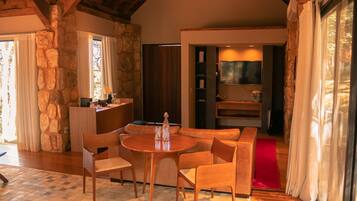 Una habitación acogedora con pared de piedra, una mesa de comedor de madera con sillas, un sofá y un televisor fijado a la pared.