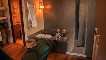 A bathroom with a large sink, towel rack, and wicker chair.