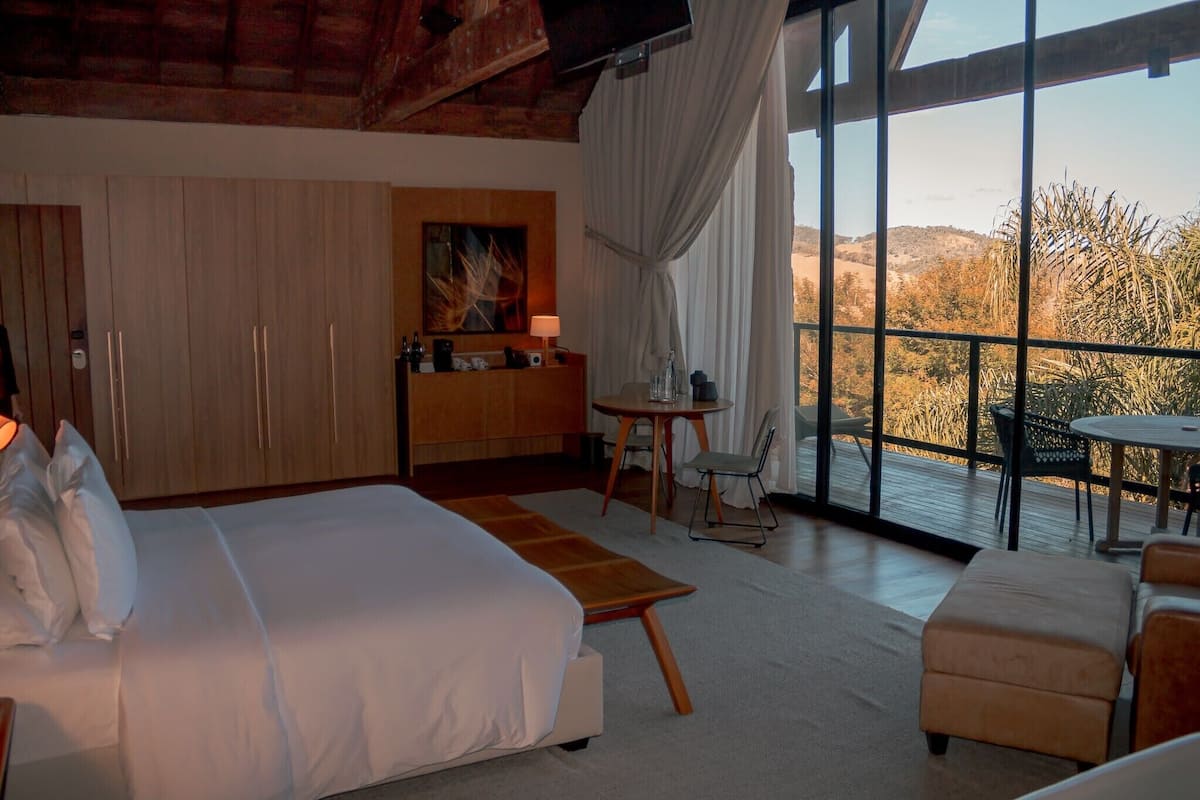 A bedroom with a large bed, a desk, and a view of the outdoors.
