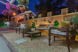An outdoor seating area with a wooden bench and a table, surrounded by potted plants and a brick wall. - Pousada Jardon (Campos do Jordão)