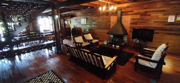 A cozy lounge area with wooden flooring, a fireplace, and comfortable seating.