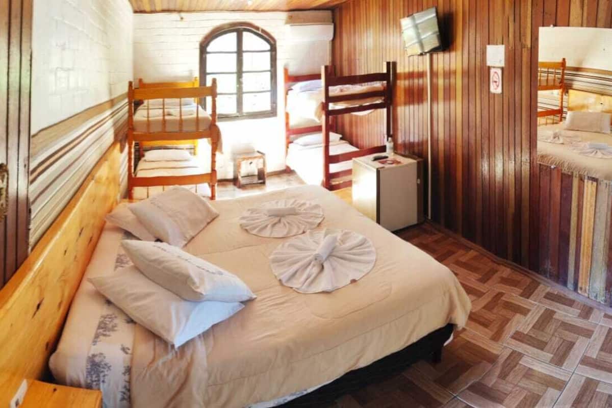 A bedroom with a wooden bed, a small bedside table, a chair, and a window.