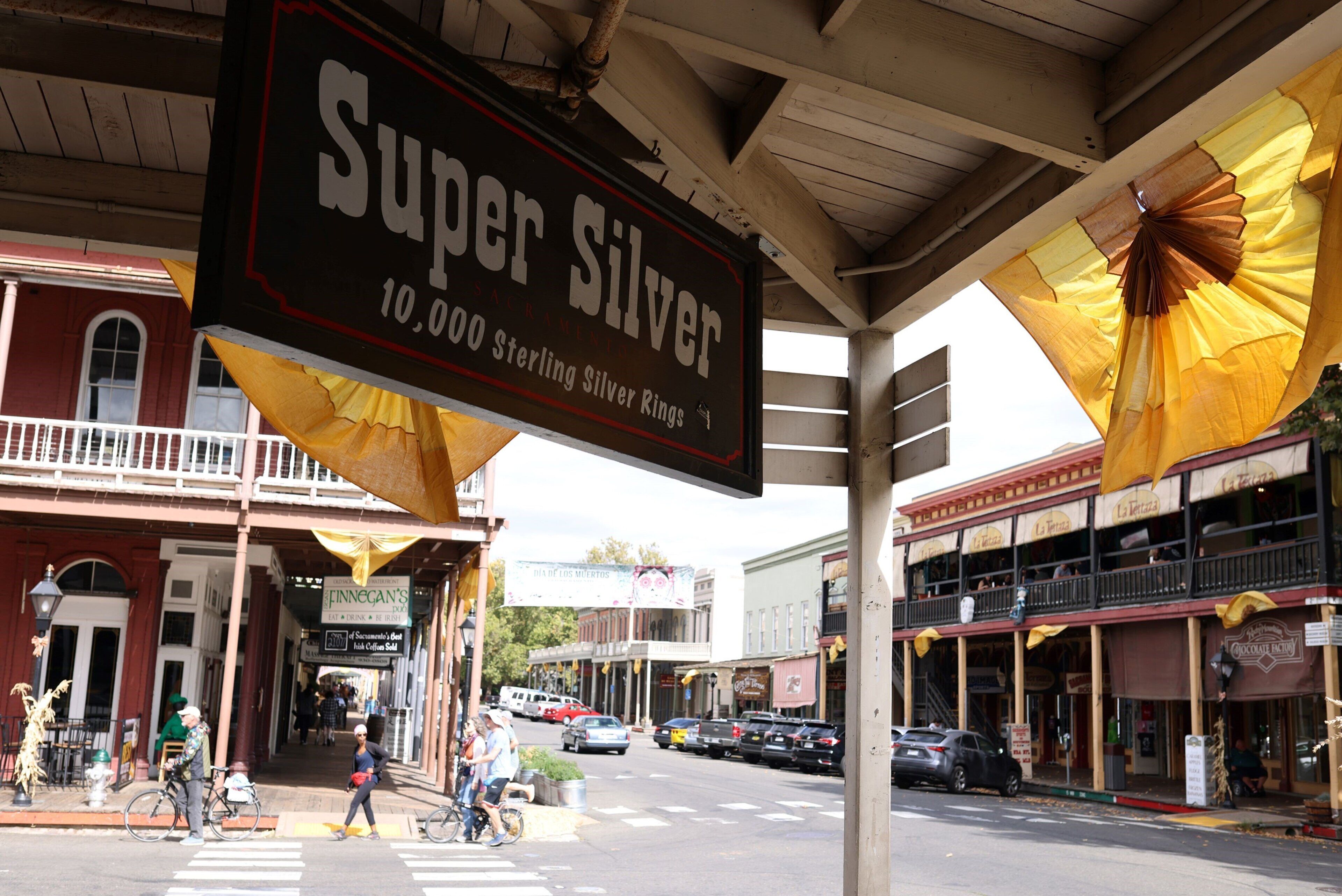 Une scène de rue avec une enseigne bien visible pour « Super Silver 10 000, bagues en argent sterling ».