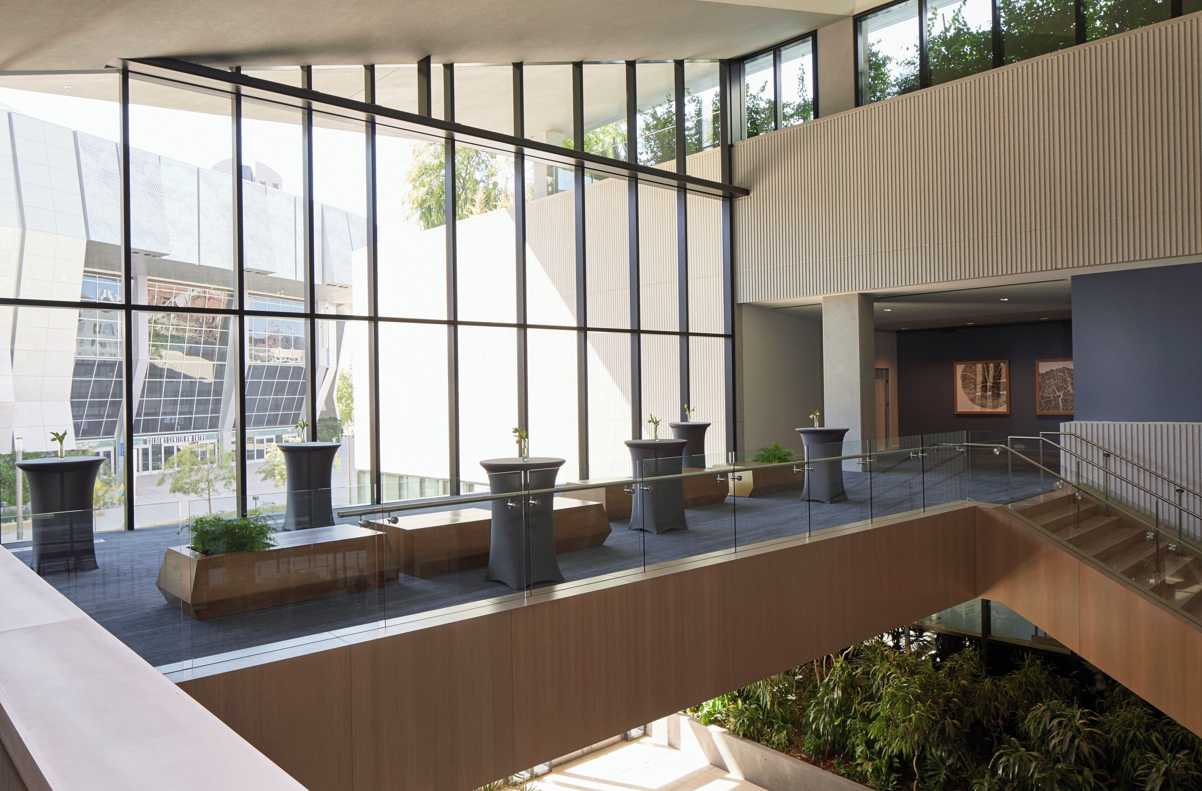 A modern interior with large windows, a staircase, and potted plants.