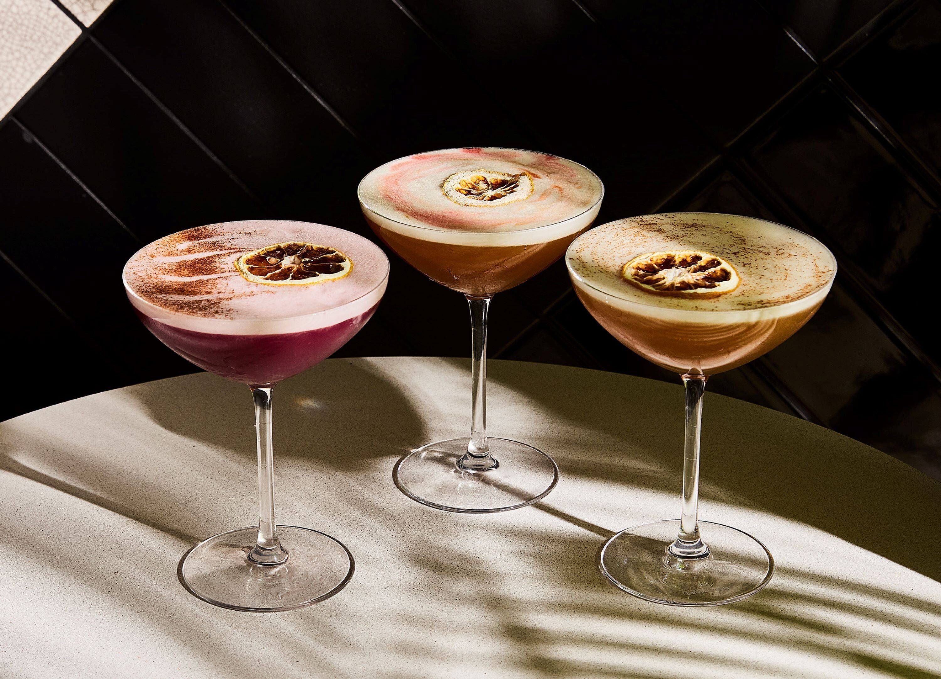 Three martini glasses with a frothy drink on a table.
