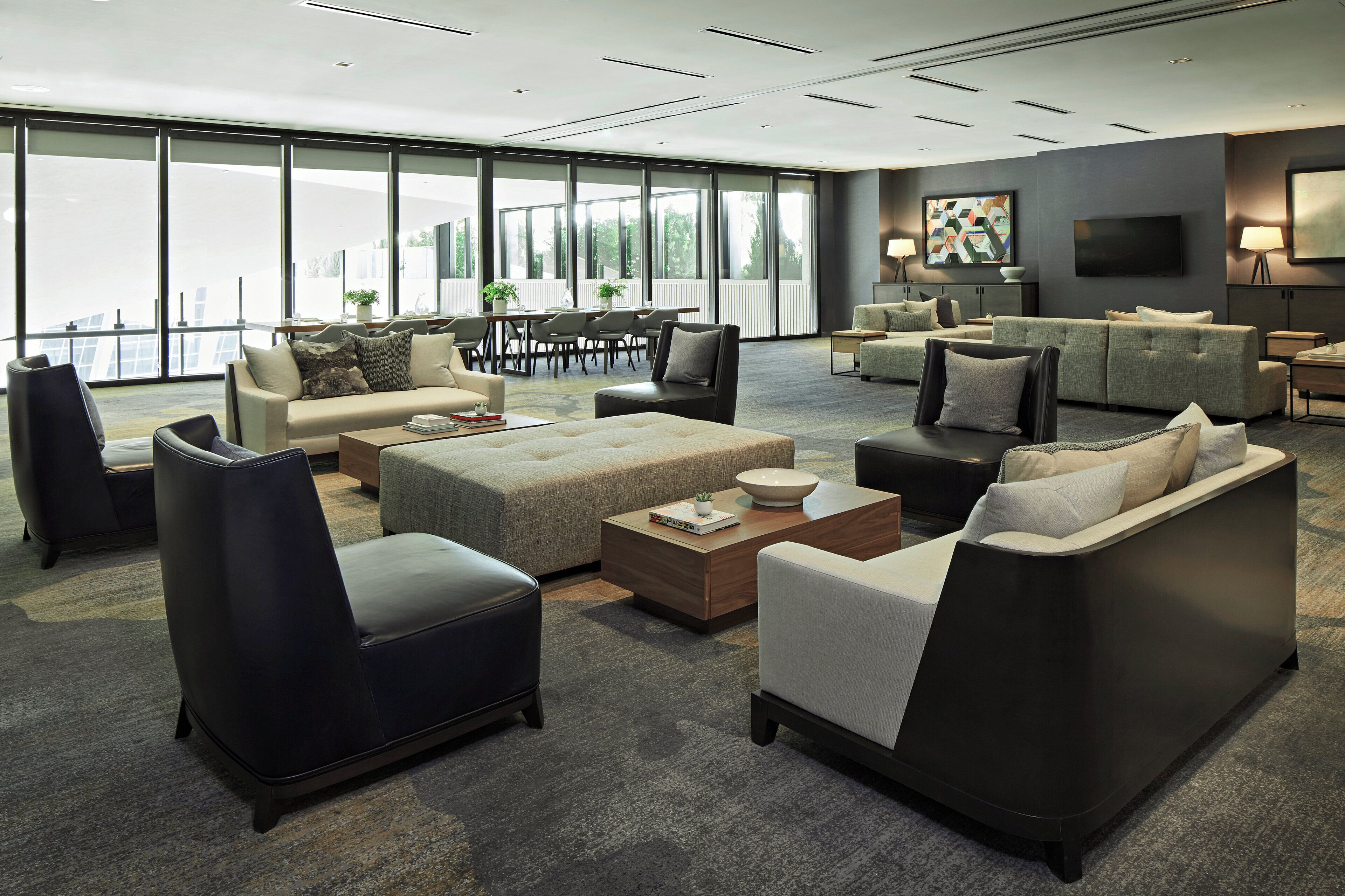 A spacious living area with multiple seating options, a large window offering a view, and a flat-screen TV mounted on the wall.