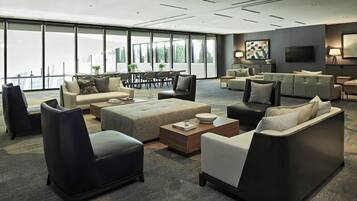A spacious living area with multiple seating options, a large window offering a view, and a flat-screen TV mounted on the wall.