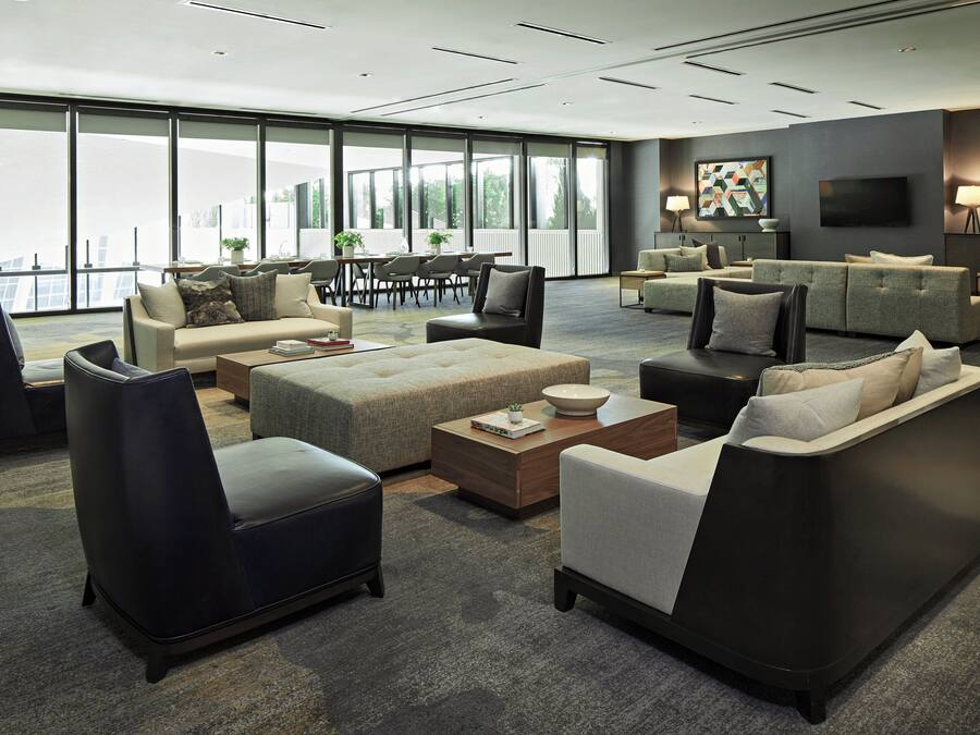 A spacious living area with multiple seating options, a large window offering a view, and a flat-screen TV mounted on the wall.