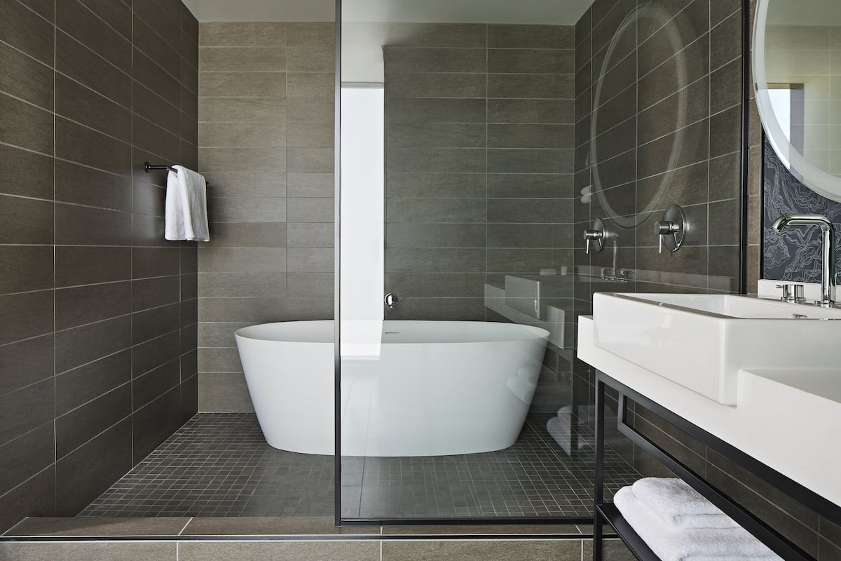 Une salle de bain moderne avec une baignoire sur pieds, une douche à parois de verre et un grand miroir au-dessus du lavabo.