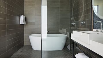 Un baño moderno con una bañera independiente, una cabina de ducha con paredes de vidrio y un espejo grande.