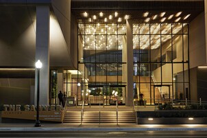 Entrada de un edificio moderno con puertas de vidrio, una escalera y un cartel que dice 'THE SAWYER 500 J SACRAMENTO KINGS'.
