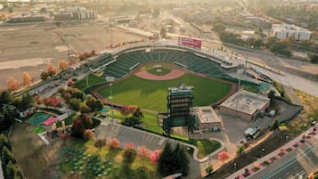 Vue aérienne d’un stade avec un terrain de baseball, entouré d’arbres et d’un parking.