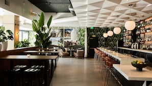 Un área de bar moderna con techo geométrico, taburetes de bar y una variedad de plantas.