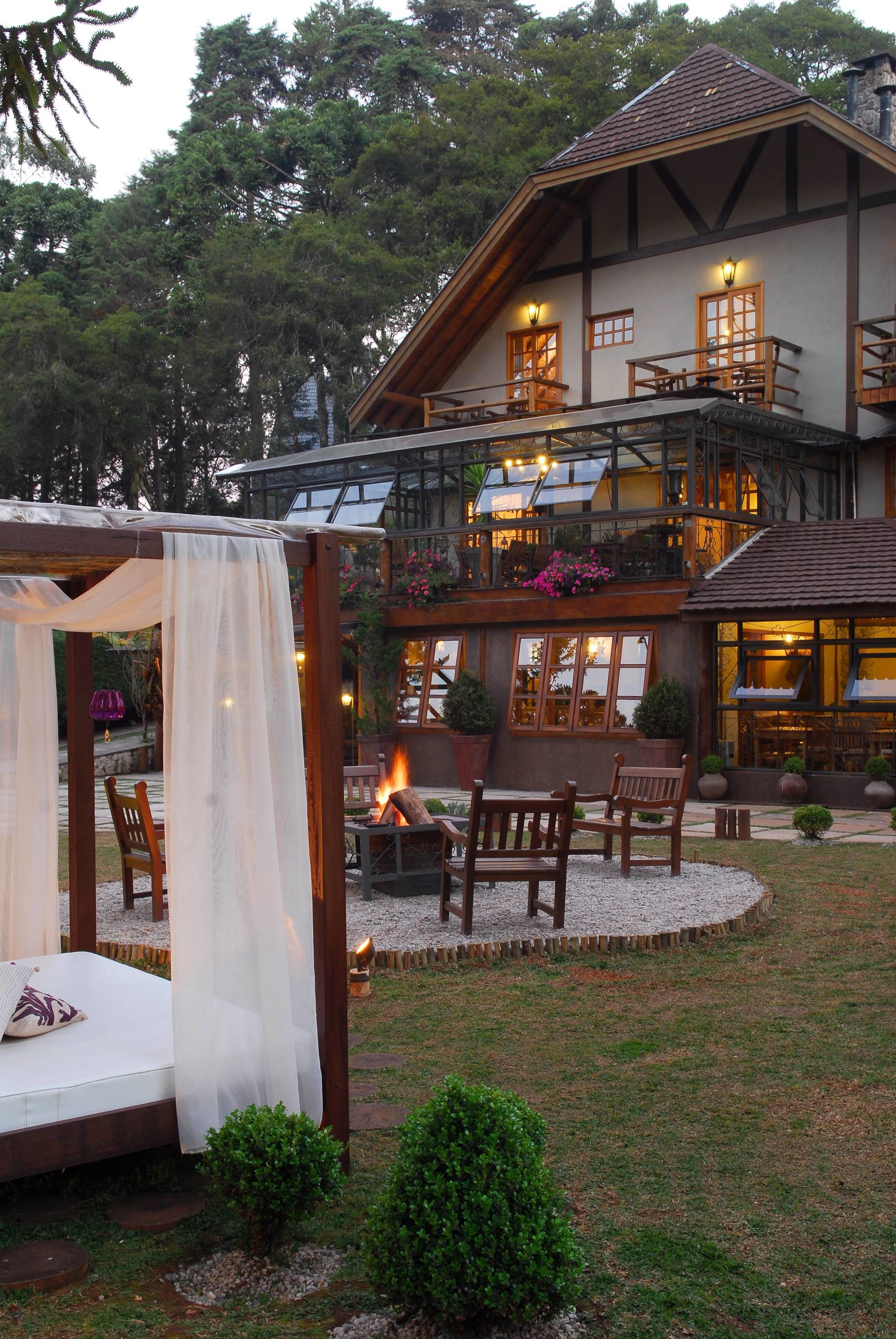 A two-story lodge with a balcony, outdoor seating area, and a fire pit.