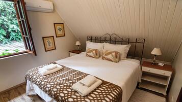 A bedroom with a bed, two bedside tables, a window, and a wall-mounted air conditioner.