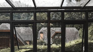 Habitació amb una finestra gran que dona a un jardí i una casa.