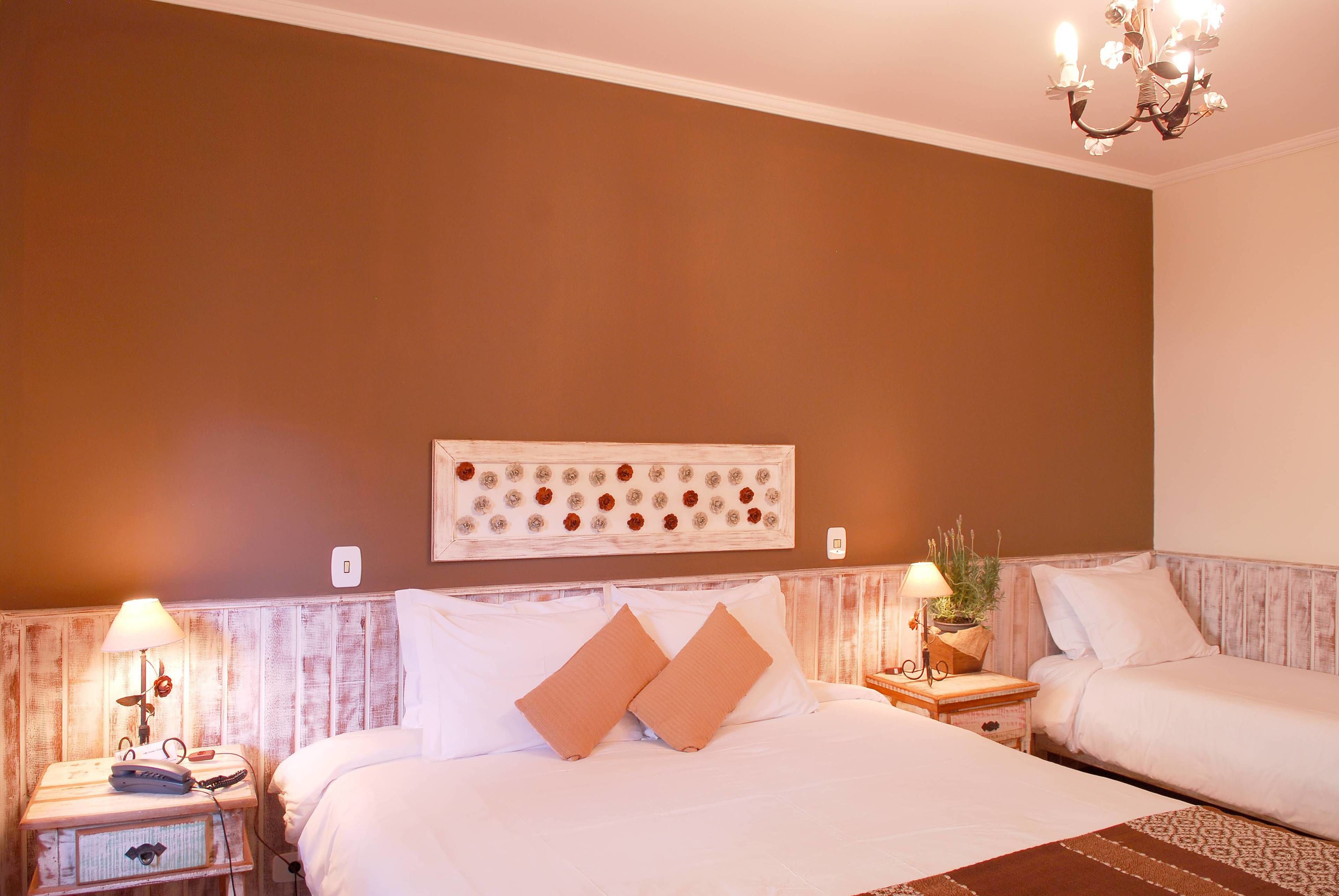 Ein Hotelzimmer mit zwei Betten, einem Wanddekor, einer Kronleuchter und einem Nachttisch mit Lampe und Telefon.