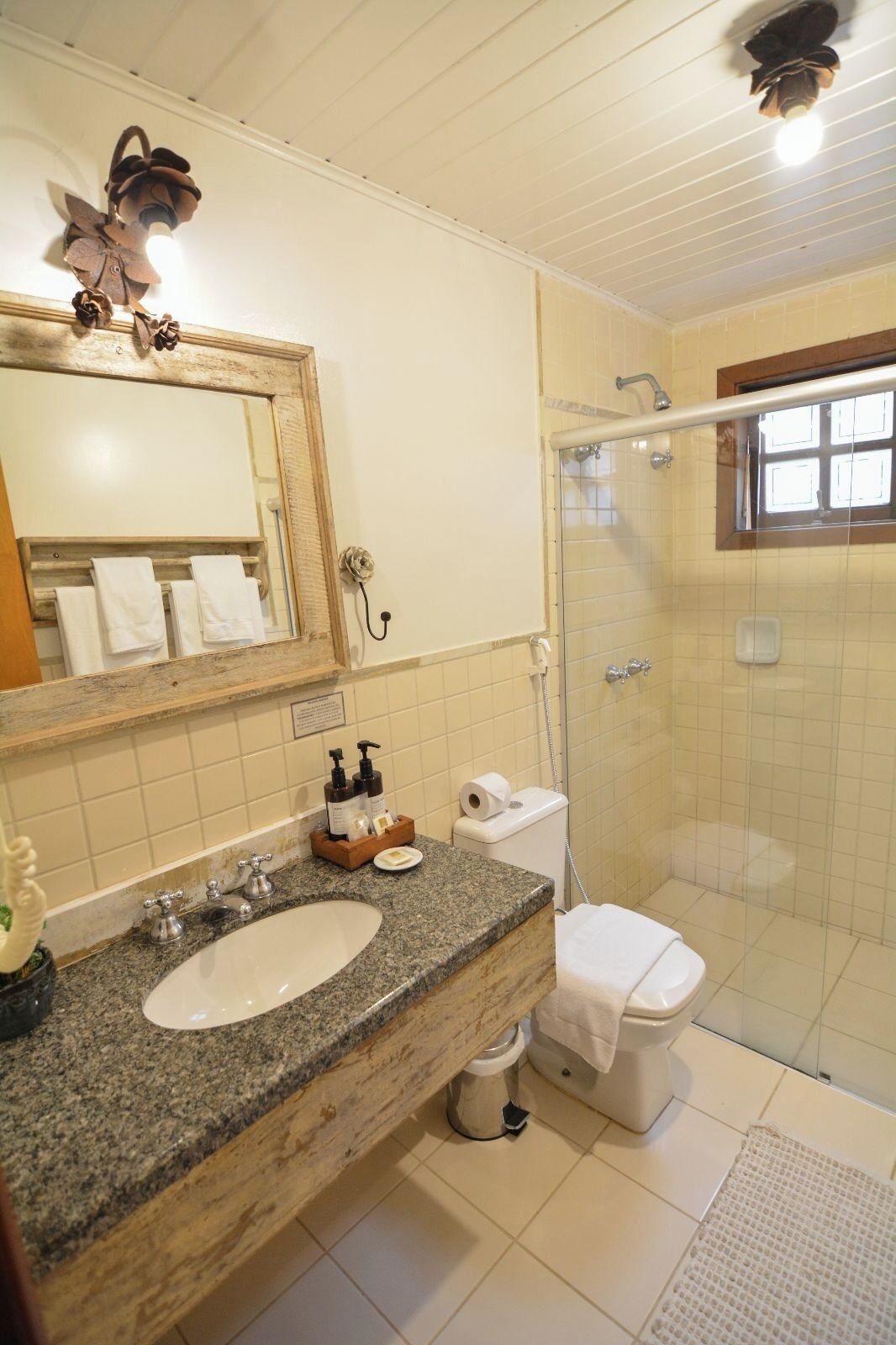 Une salle de bain avec un lavabo en granit, un miroir, des toilettes et une douche.