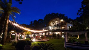 Una casa espaiosa amb un balcó, envoltada d'un jardí ben il·luminat a la nit.
