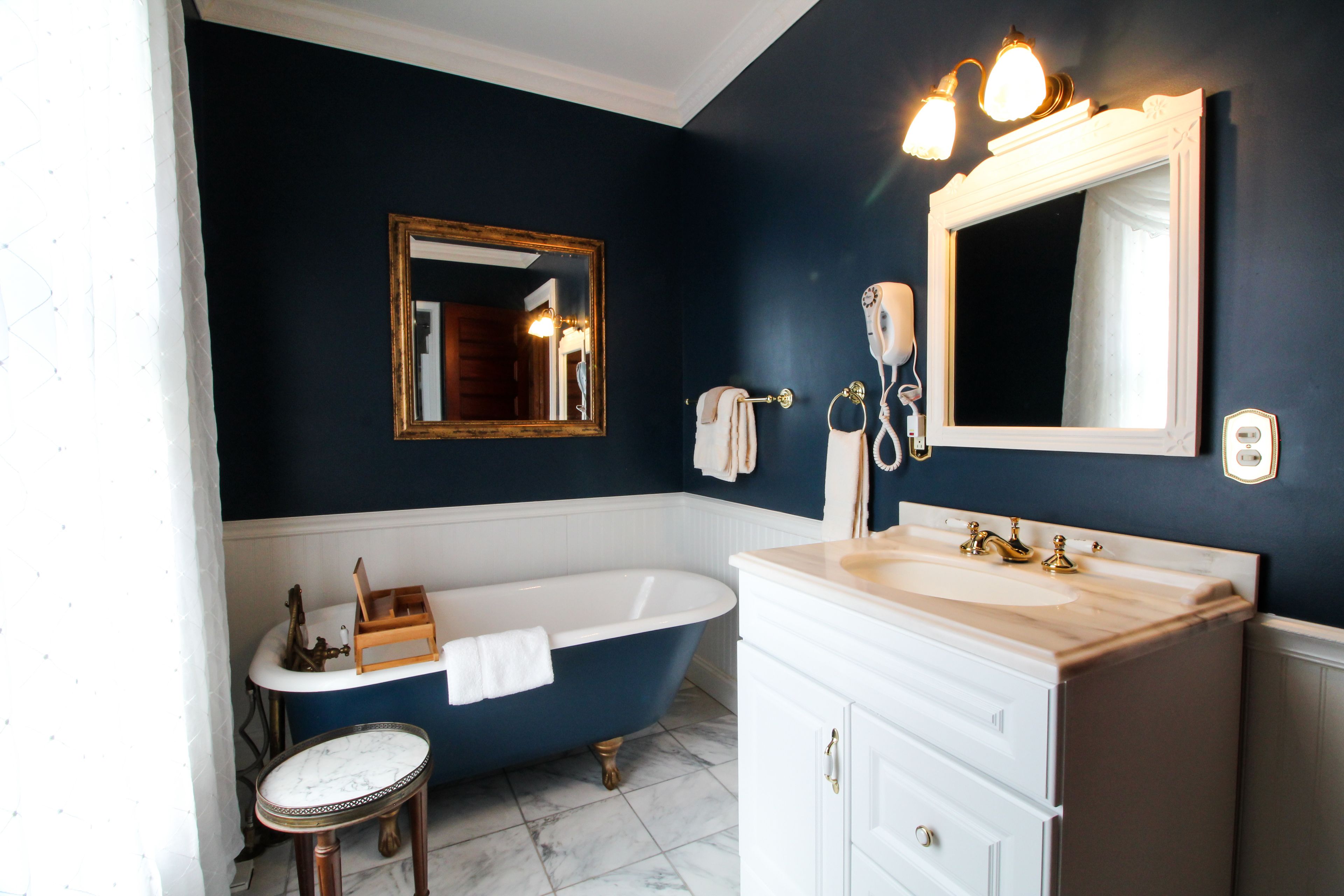 A bathroom with a bathtub, a vanity with a sink, a mirror, and a towel rack.