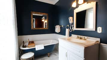 A bathroom with a bathtub, a vanity with a sink, a mirror, and a towel rack.