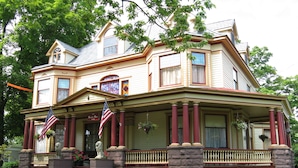 A Victorian-style house with a front porch, a statue, and two American flags. - 1897 Beekman House (Dundee)