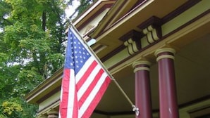 A building with a porch, a flag, and a lion statue. - 1897 Beekman House (Dundee)