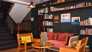 Un salon chaleureux avec un escalier, une table ronde en bois, un canapé et une bibliothèque remplie de livres.