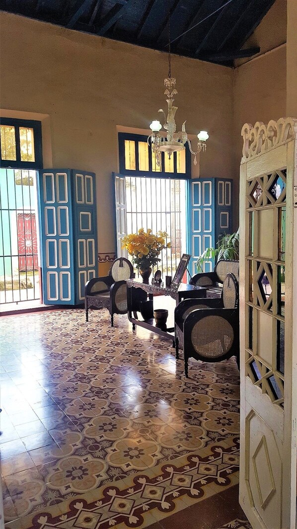 A room with a patterned floor, a chandelier, and blue doors. - Hostal Los Vitrales (Remedios)