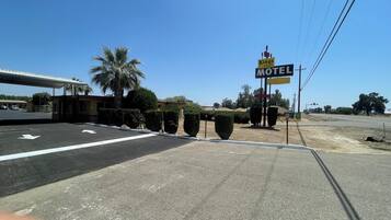 A motel sign with a clear view of the parking lot and surrounding landscaping.