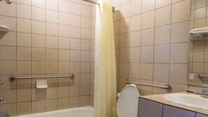 A bathroom with a bathtub, toilet, and sink. - Kings Rest Motel (Lemoore)