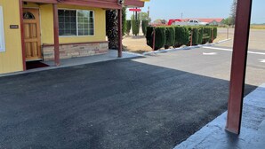A yellow building with a red awning, a sign that reads "HOTEL", and a parking area in front. - Kings Rest Motel (Lemoore)
