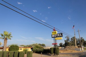 Une enseigne de motel avec un drapeau américain, entourée d’un palmier et d’un bâtiment en arrière-plan.
