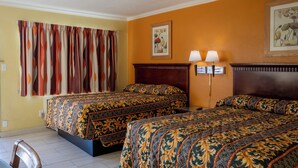 A hotel room with two beds, a wooden headboard, a nightstand with two lamps, and a framed picture on the wall. - Kings Rest Motel (Lemoore)