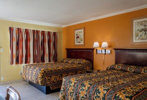 Une chambre d’hôtel avec deux lits, une tête de lit en bois, une table de chevet avec deux lampes et un tableau encadré au mur.