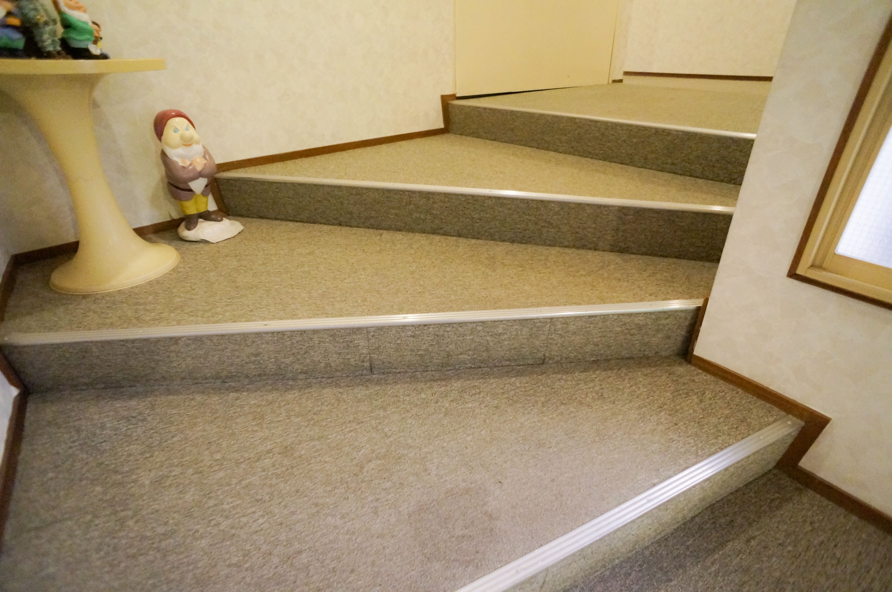 Una escalera alfombrada con una pequeña figurina en el descansillo.