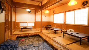 Una habitación japonesa tradicional con suelo de tatami, mesas bajas y puertas correderas.