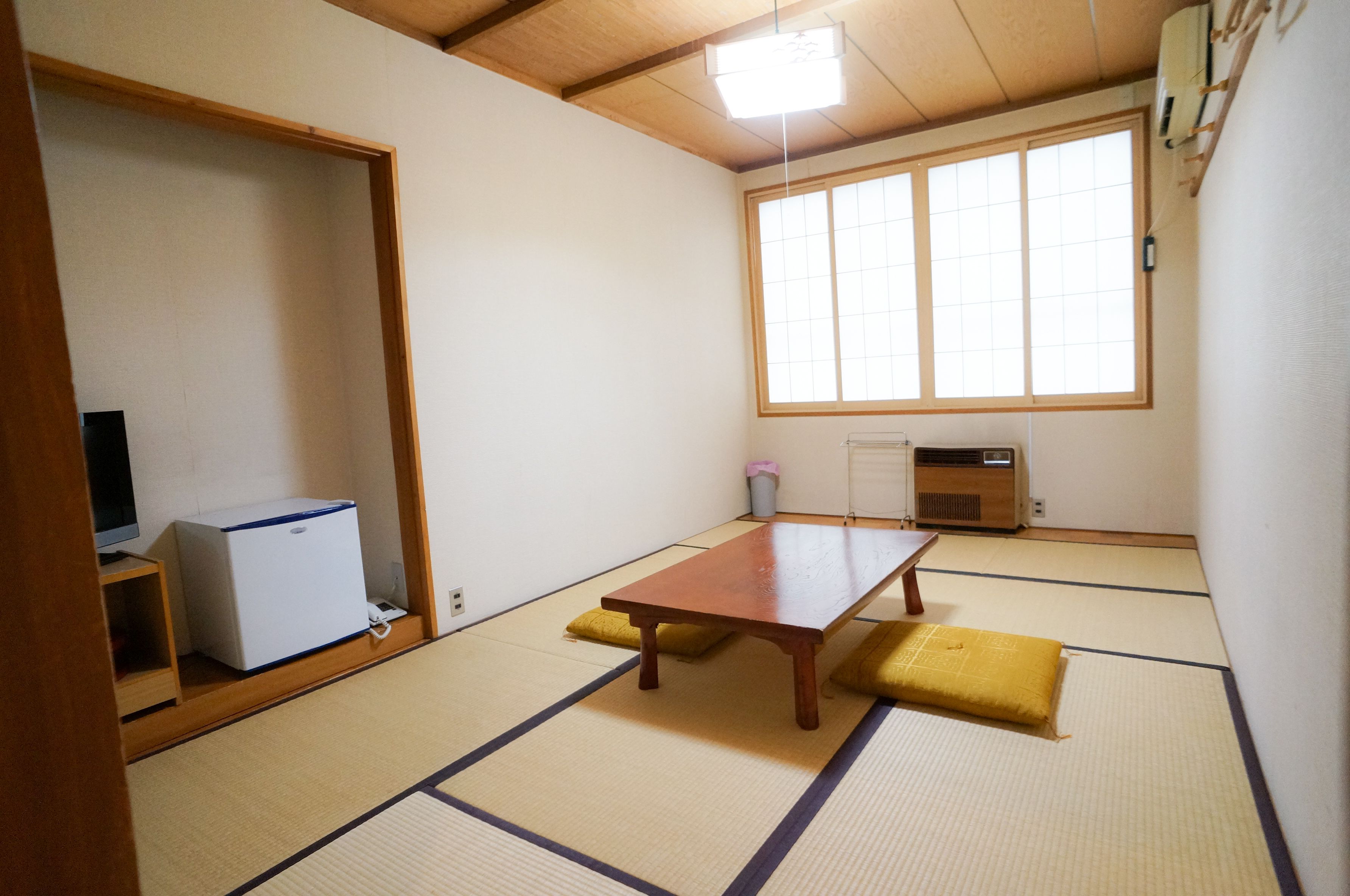 Ett traditionellt japanskt rum med tatamimattor på golvet, ett träbord, en tv och en värmare.