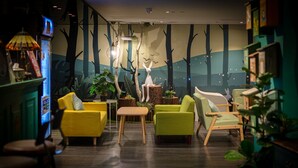 A cozy indoor seating area with yellow and green chairs, a small table, and a decorative rabbit sculpture. - Finders Hotel-Fu Qian (Taipei)