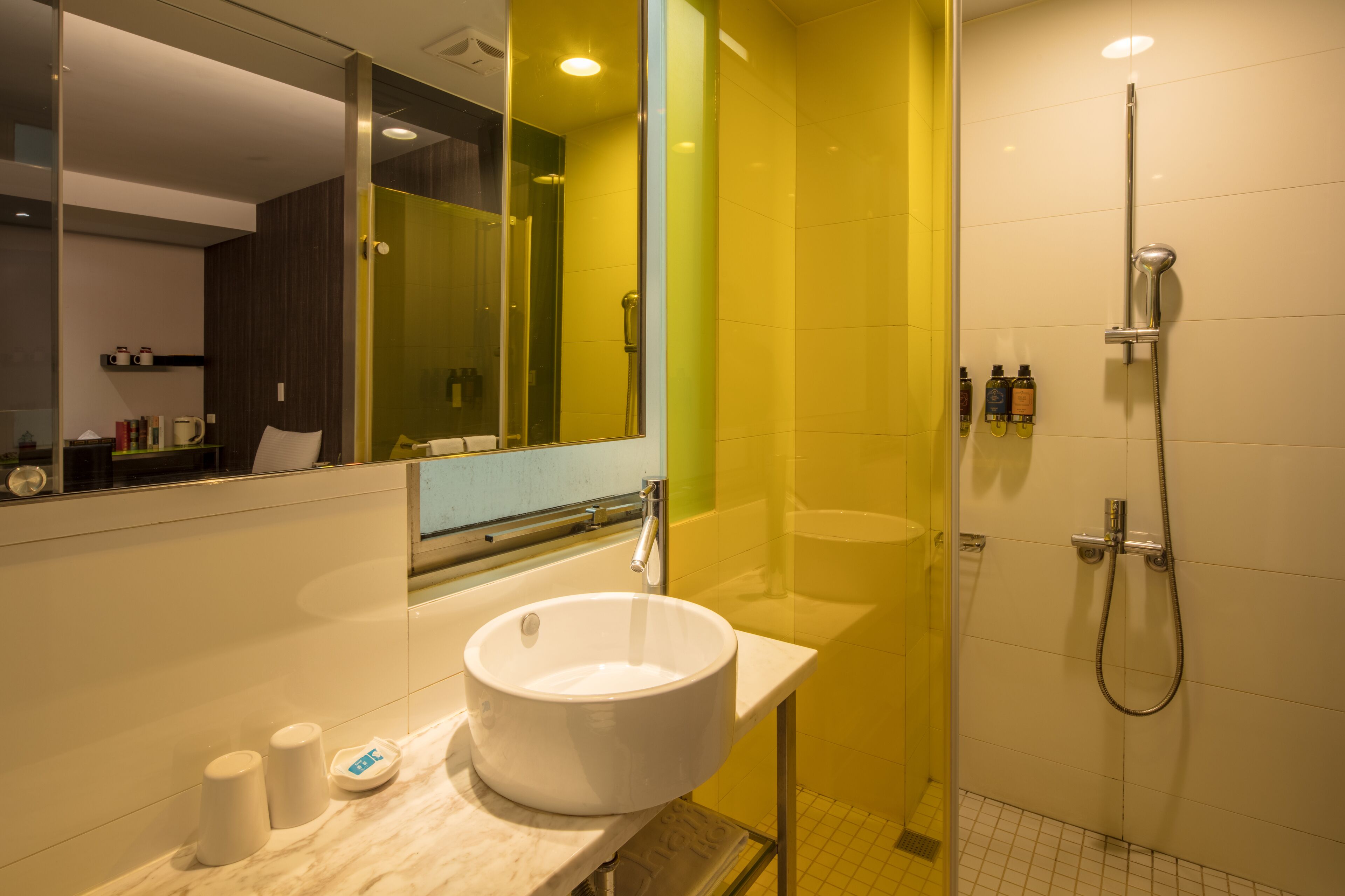 A modern bathroom with a large mirror, a white sink, and a glass-enclosed shower area.