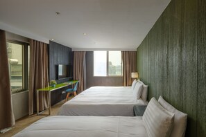 Quarto de hotel com duas camas, uma escrivaninha, uma cadeira, uma televisão e uma janela com cortinas.