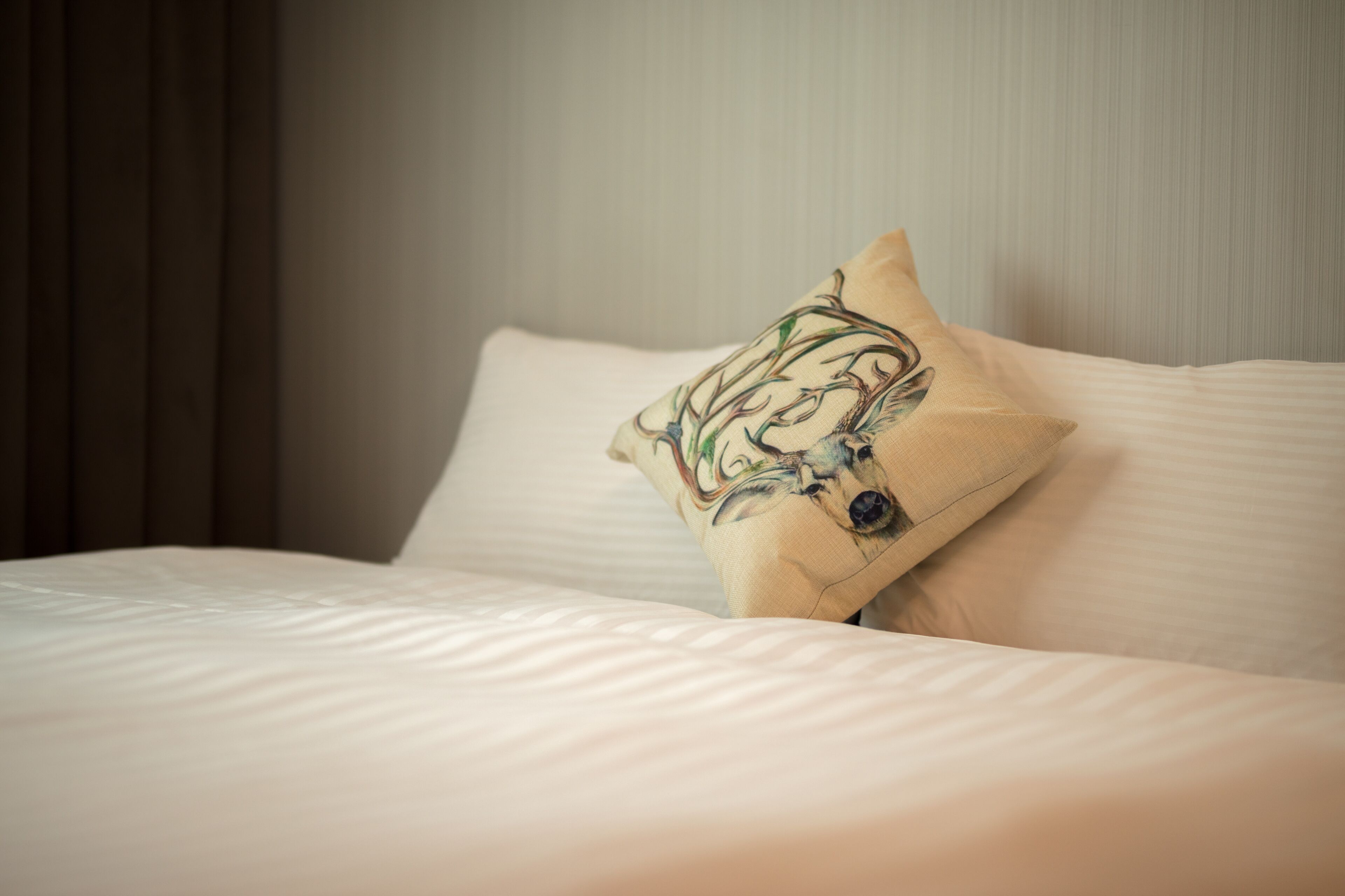 A neatly made bed with a pillow featuring a floral design.