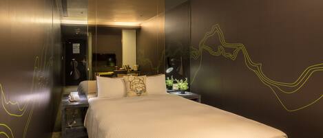 A hotel room with a large bed, a bedside table with a lamp, a mirror, and a wall with abstract line art.