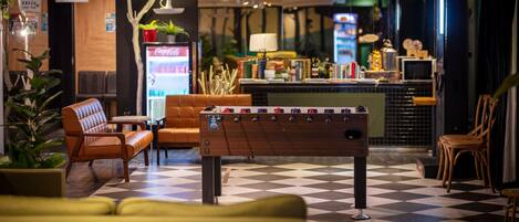 A lobby with a foosball table, seating area, and a bar.