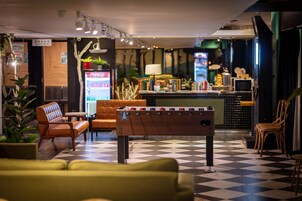 Een lobby met een tafelvoetbaltafel, een zithoek en een bar.