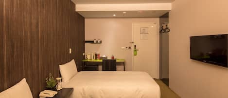 Habitación de hotel con dos camas, un escritorio, una silla, un televisor y una puerta.