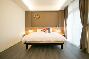 Una habitación de hotel moderna con una cama grande, cabecera de madera, lámparas de noche y un reloj de pared.